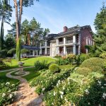 Beautiful luxury villa surrounded by manicured garden and lush landscaping on a sunny day.